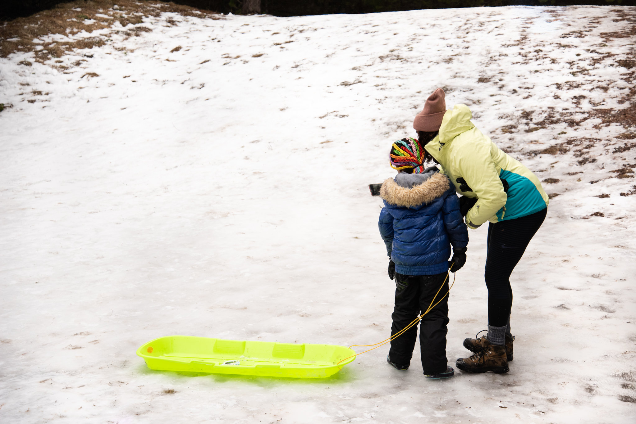 A child and adult prepare to sled. 