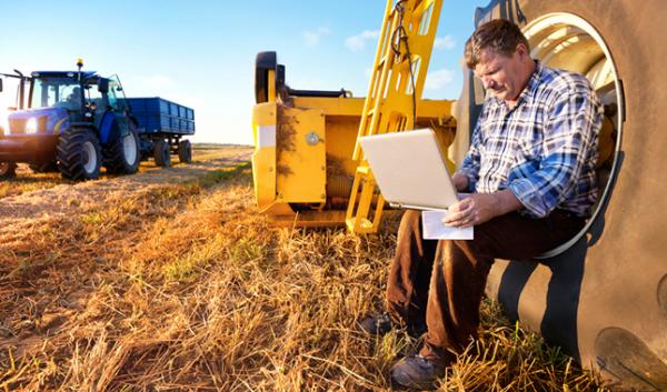 man working on laptop while sitting in tractor wheel